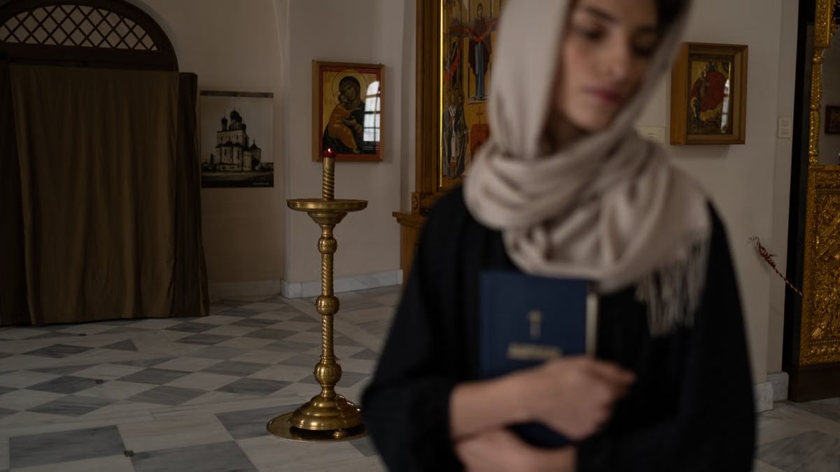 Woman with headscarf holding book in serene church setting, embodying spirituality.